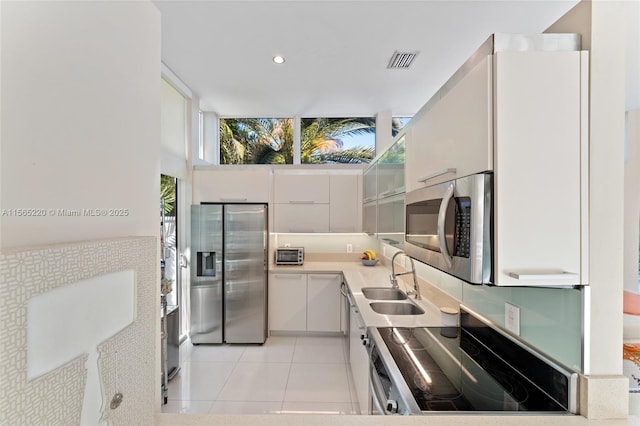 kitchen with white cabinetry, appliances with stainless steel finishes, sink, and light tile patterned flooring