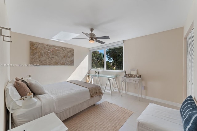 bedroom featuring ceiling fan, a skylight, and a closet