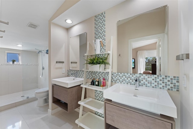 bathroom featuring tasteful backsplash, vanity, tiled shower, toilet, and tile patterned floors