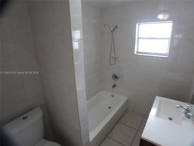 full bathroom with tiled shower / bath combo, tile patterned flooring, toilet, vanity, and tile walls