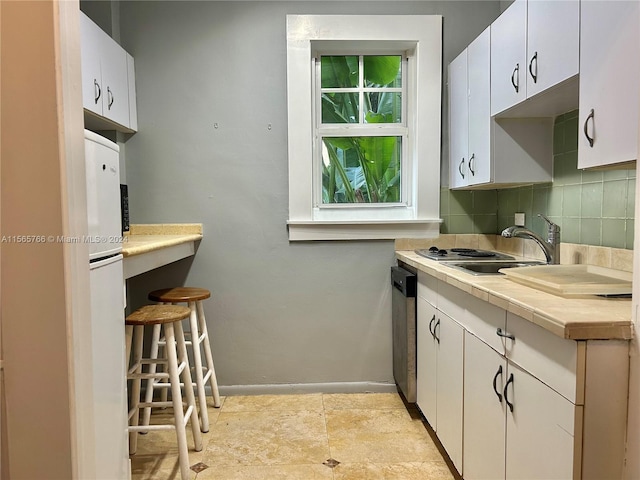 kitchen with tasteful backsplash, white cabinetry, white refrigerator, and sink