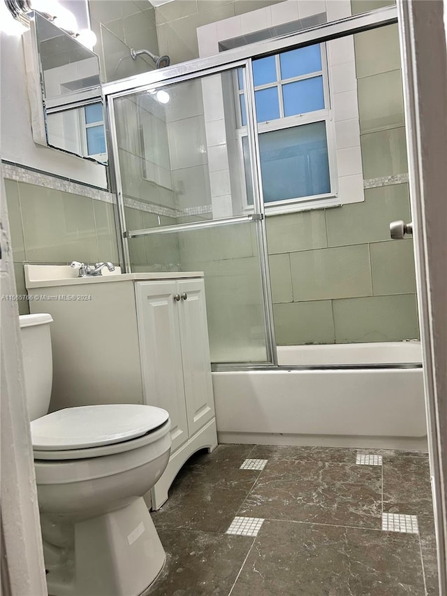 full bathroom with bath / shower combo with glass door, vanity, and toilet