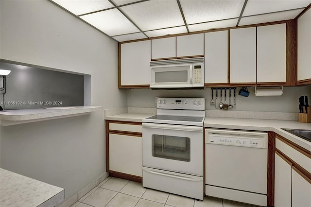 kitchen featuring white cabinets, a paneled ceiling, light tile flooring, and white appliances