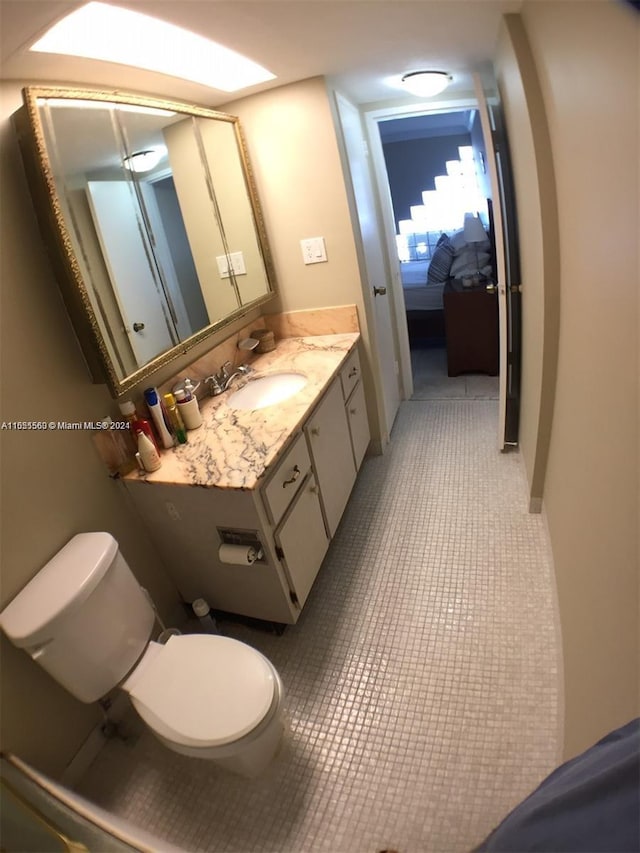 bathroom with tile flooring, toilet, and vanity