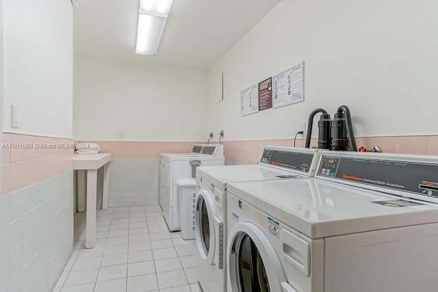 washroom with tile walls, light tile floors, and washing machine and dryer