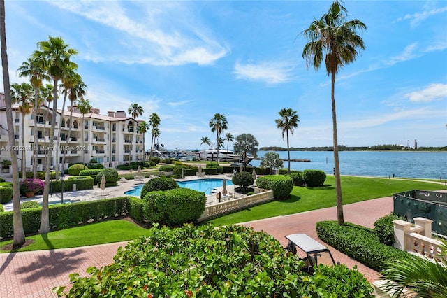 view of community with a water view, a swimming pool, and a lawn