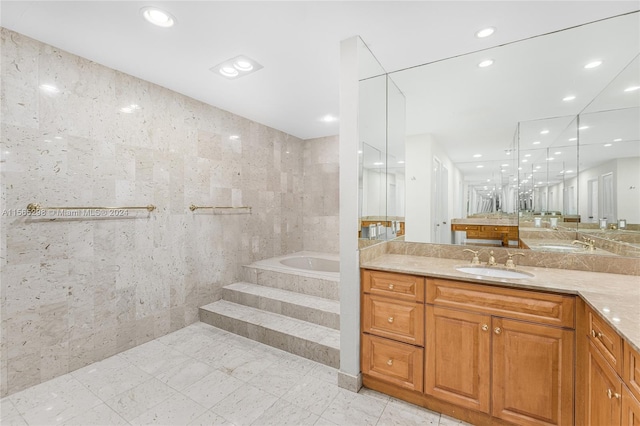 bathroom featuring vanity, tile walls, a relaxing tiled tub, and tile patterned flooring