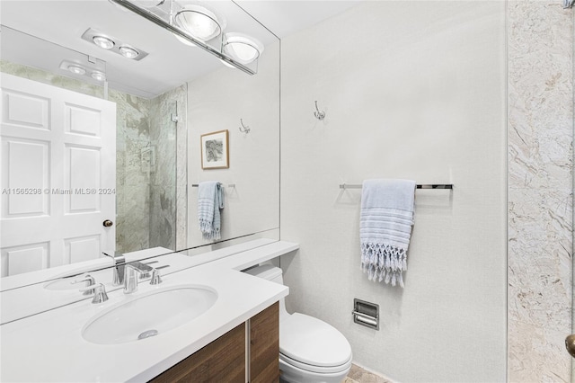 bathroom with vanity, toilet, and tiled shower