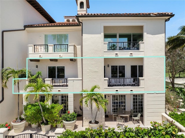 rear view of property featuring a patio area and a balcony