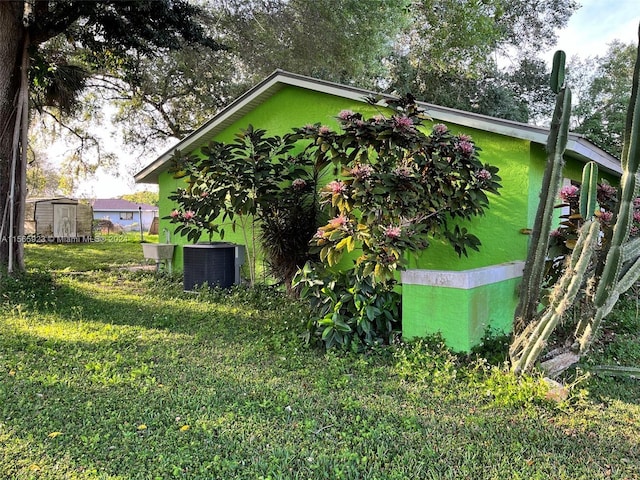 view of home's exterior with a shed, a lawn, and central air condition unit