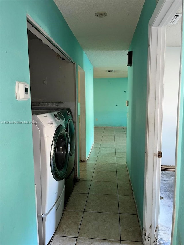 clothes washing area featuring tile floors and washing machine and dryer