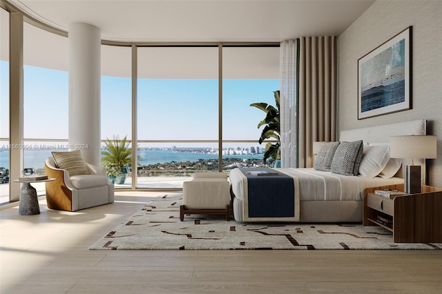 bedroom featuring floor to ceiling windows, light wood-type flooring, and a water view