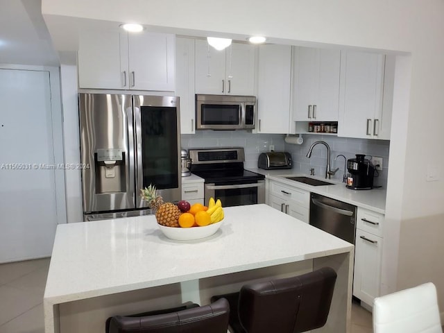 kitchen with a breakfast bar, tasteful backsplash, white cabinetry, stainless steel appliances, and sink