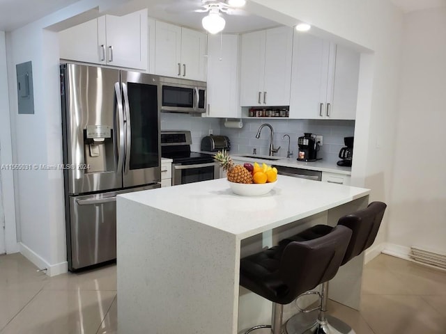 kitchen featuring backsplash, a breakfast bar area, appliances with stainless steel finishes, and ceiling fan