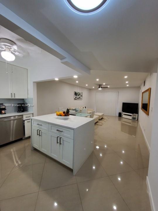 kitchen with a kitchen island, light tile flooring, ceiling fan, white cabinetry, and dishwasher