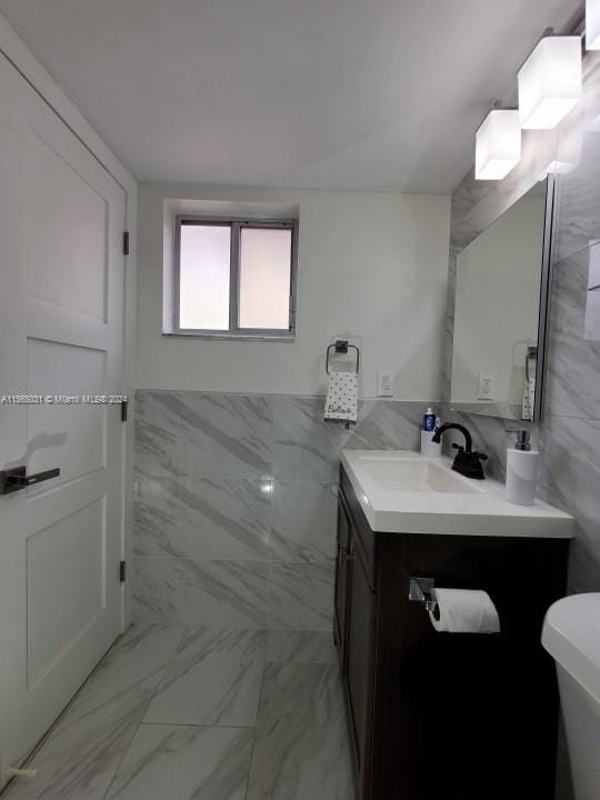 bathroom with tile walls, toilet, vanity with extensive cabinet space, and tile flooring