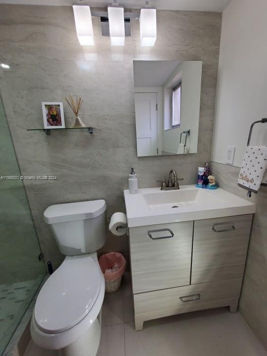 bathroom featuring toilet, vanity, and tile walls