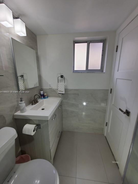 bathroom featuring tile flooring, toilet, and vanity with extensive cabinet space