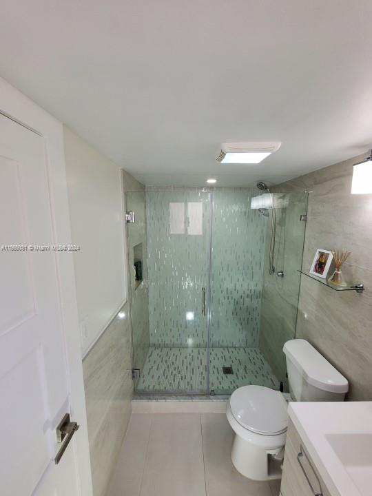 bathroom featuring tile floors, toilet, vanity, and an enclosed shower