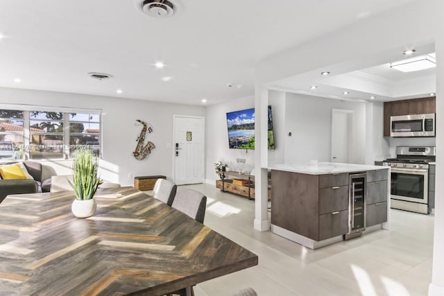 dining area with a tray ceiling, light tile floors, and wine cooler