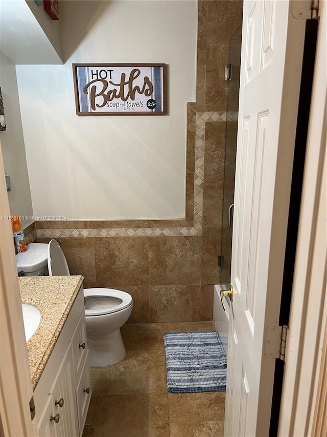 bathroom featuring tile walls, tile floors, vanity, and toilet