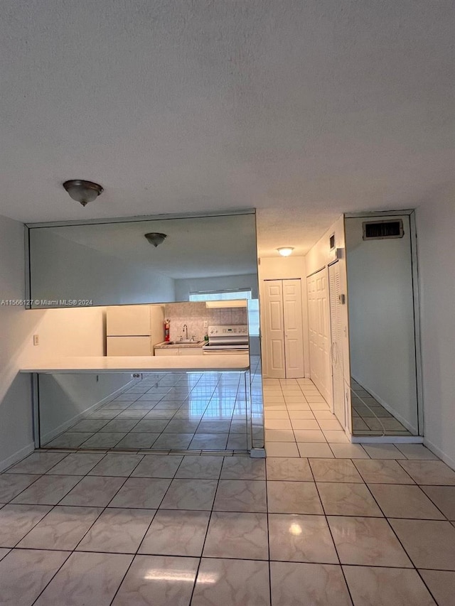 interior space with tile patterned floors, sink, and a textured ceiling