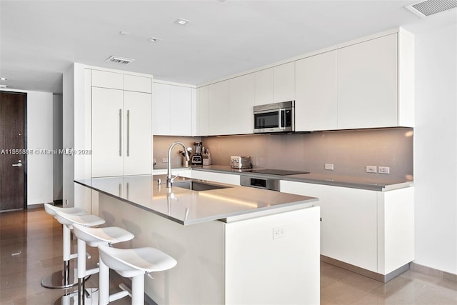 kitchen with a kitchen breakfast bar, white cabinets, sink, and a kitchen island with sink