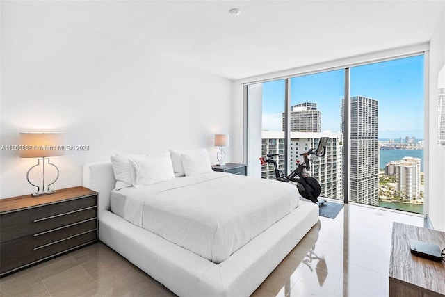 bedroom featuring a water view, a wall of windows, and light tile floors