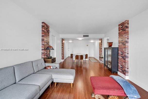 living room featuring a brick fireplace, brick wall, and dark hardwood / wood-style floors