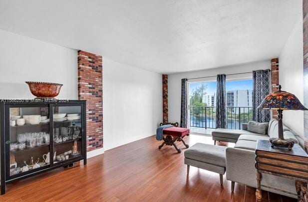 living area featuring dark hardwood / wood-style flooring and brick wall