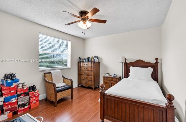 bedroom featuring ceiling fan, hardwood / wood-style floors, and a textured ceiling