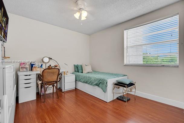 bedroom featuring hardwood / wood-style floors, a textured ceiling, and ceiling fan