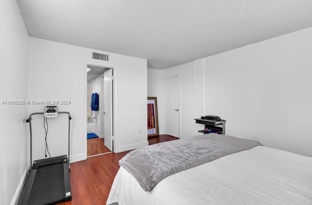 bedroom featuring ensuite bath and dark hardwood / wood-style floors