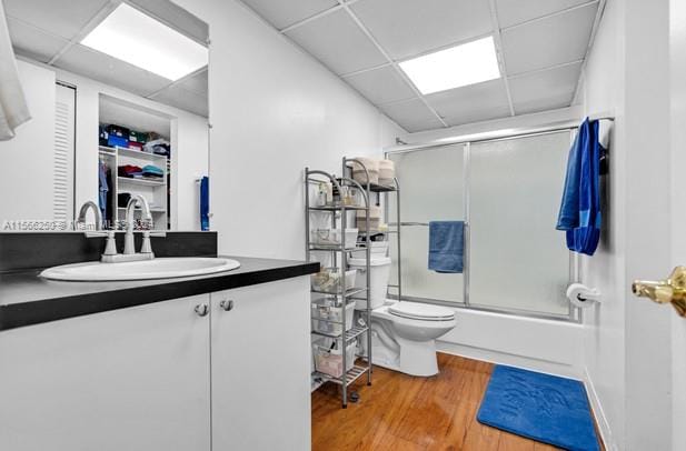 full bathroom with shower / bath combination with glass door, a drop ceiling, large vanity, and wood-type flooring