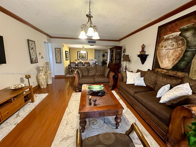 living room featuring hardwood / wood-style flooring, crown molding, an inviting chandelier, and a textured ceiling