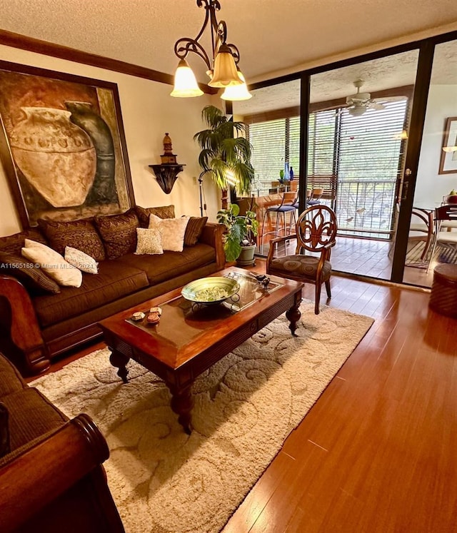 living room with hardwood / wood-style floors, ornamental molding, expansive windows, a textured ceiling, and a chandelier