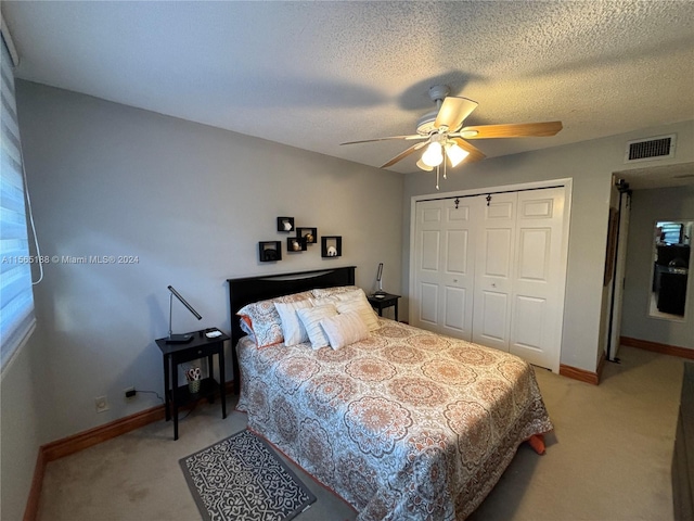 carpeted bedroom with ceiling fan, a textured ceiling, and a closet