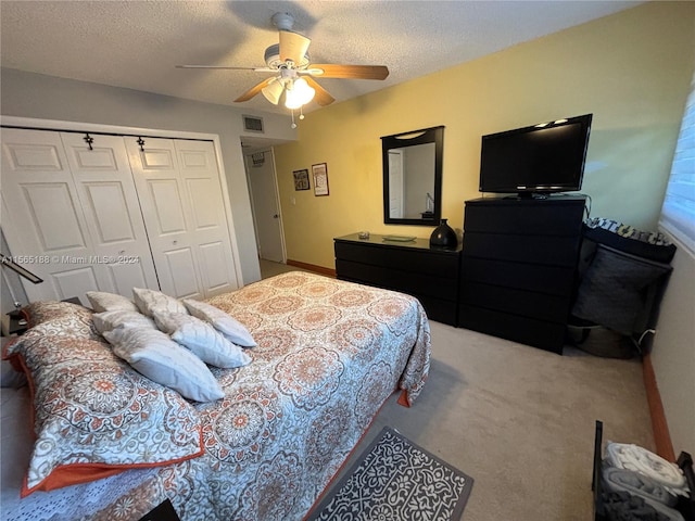 bedroom with ceiling fan, light colored carpet, a textured ceiling, and a closet