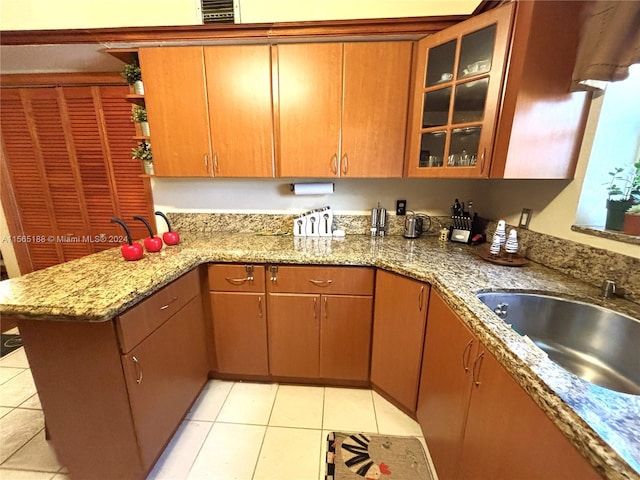 kitchen featuring light tile patterned flooring, kitchen peninsula, sink, and stone counters