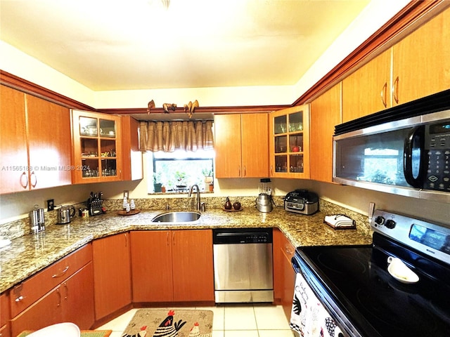 kitchen with light tile patterned flooring, appliances with stainless steel finishes, light stone countertops, and sink