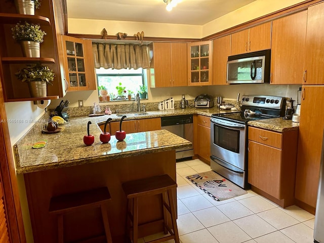 kitchen with light stone counters, sink, light tile patterned floors, and stainless steel appliances