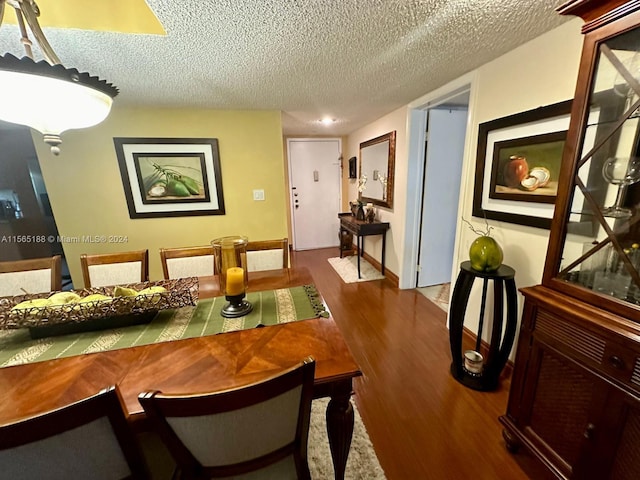 dining room with dark wood-type flooring and a textured ceiling