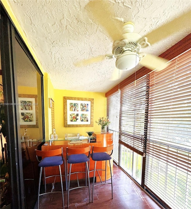 dining room with dark wood-type flooring, ceiling fan, and a textured ceiling