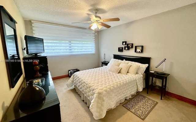 bedroom with ceiling fan, light colored carpet, and a textured ceiling