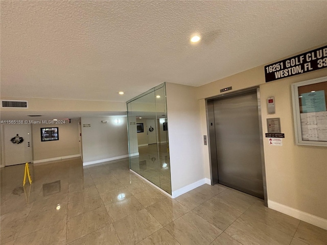 corridor featuring a textured ceiling and elevator