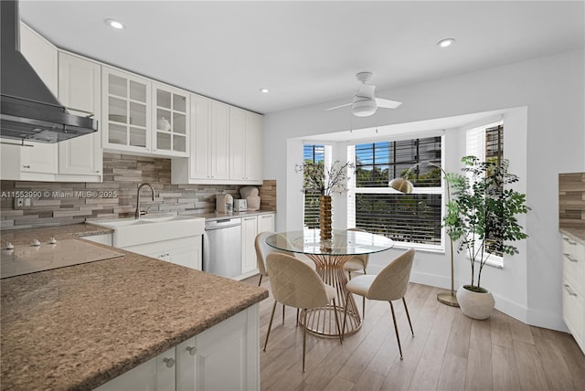 kitchen featuring wall chimney range hood, backsplash, black electric stovetop, white cabinets, and stainless steel dishwasher