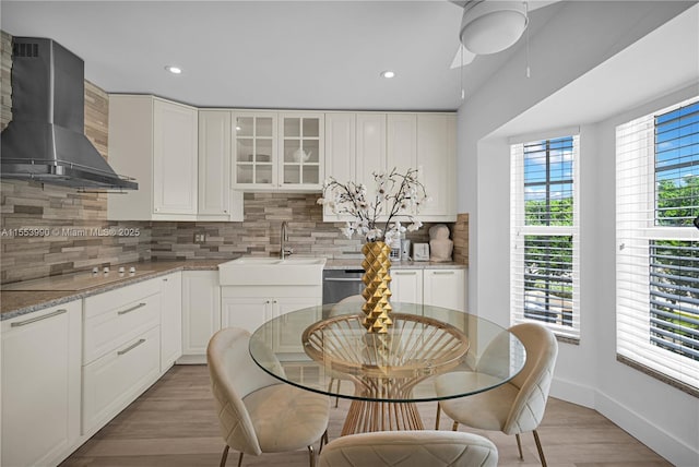 kitchen with tasteful backsplash, white cabinetry, electric stovetop, light stone countertops, and wall chimney exhaust hood