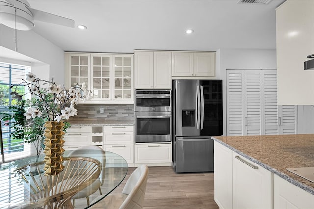 kitchen featuring white cabinetry, appliances with stainless steel finishes, ceiling fan, light stone countertops, and light hardwood / wood-style floors