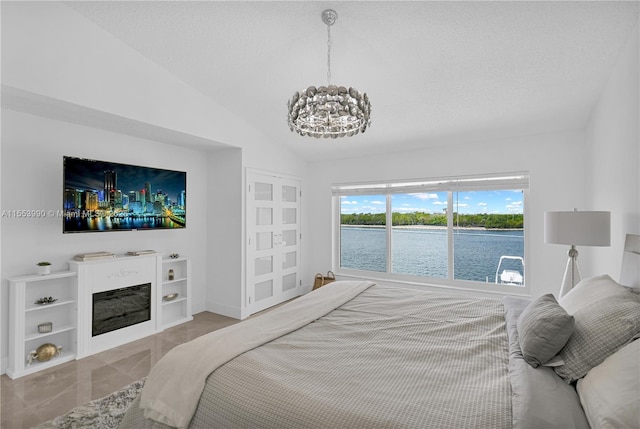 bedroom featuring lofted ceiling, a textured ceiling, and a chandelier