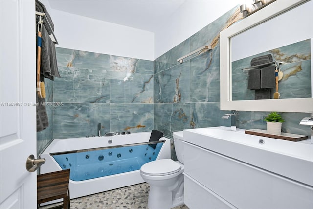 bathroom with vanity, toilet, a bathtub, and tile walls